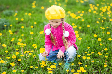 漂亮的孩子挑选鲜花在春天绿色的草地上