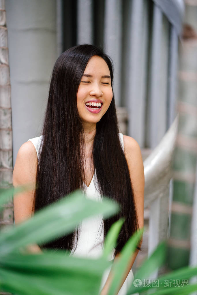 一个年轻的, 漂亮的中国职业女性的肖像站在一个未来的建筑在白天.