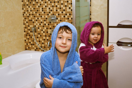 浴室里的浴衣的可爱的孩子。愉快的兄弟和姐妹水治疗以后