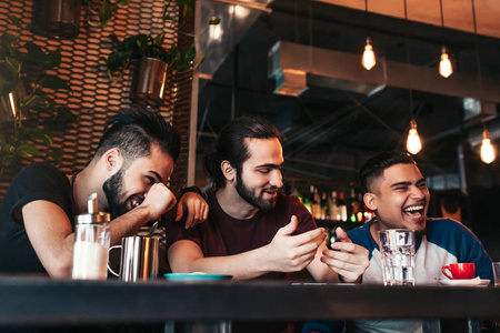 快乐的阿拉伯青年男子挂在阁楼咖啡馆。一群混合的种族人在休息室酒吧乐趣