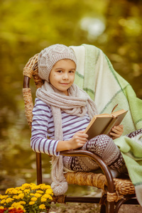 读一本书在户外的女孩。休息休息在秋天的公园里的孩子