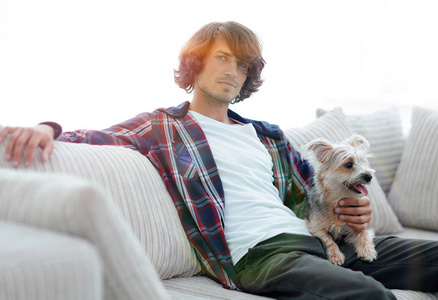 时尚的家伙坐在沙发上与他的狗