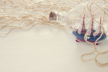 在白色木桌上的瓶子里用白色网眼和帆船的航海概念图