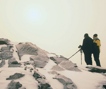 两个人在雪山上享受冬天的 photographying。自然摄影师