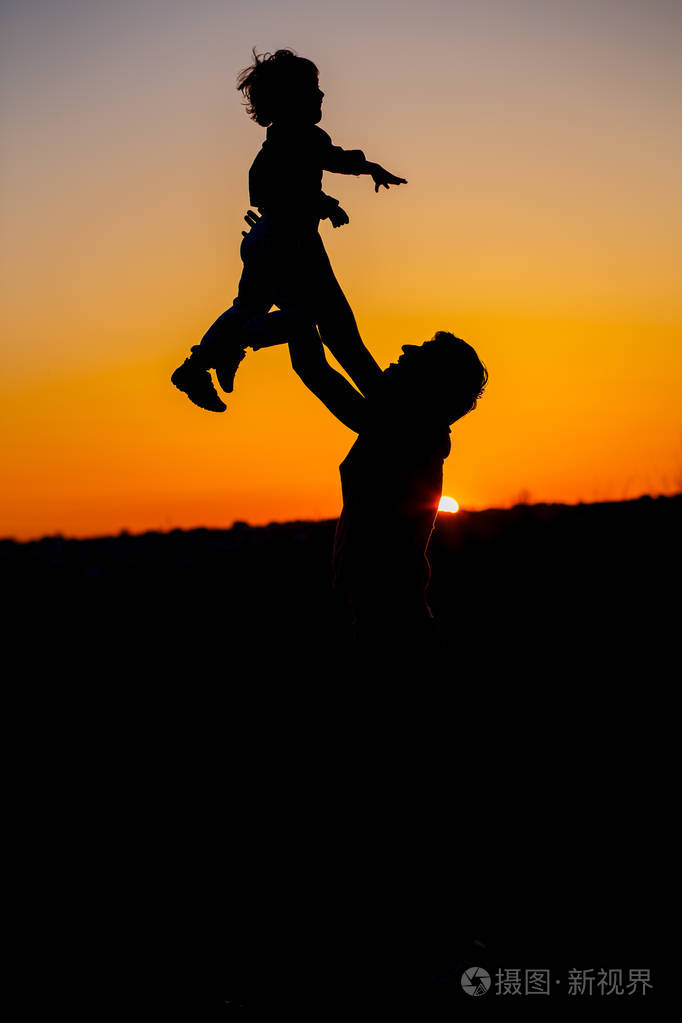幸福的家庭.父亲.孩子和他爸爸在玩.家庭作为剪影在日落.垂直照片