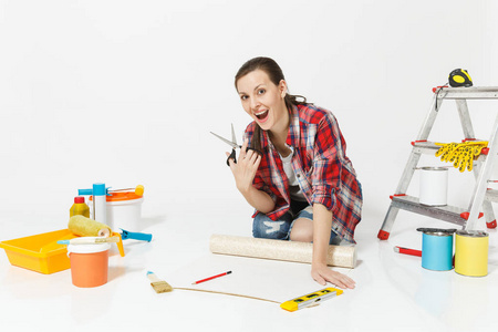 妇女坐与墙纸卷, 大剪刀, 铅笔, 在白色背景被隔绝的整修公寓的仪器。胶水配件, 喷漆工具。修复家庭概念。复制空间