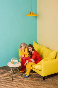 复古风格的妇女坐在黄色沙发上与水族馆的鱼在五颜六色的公寓咖啡桌, 娃娃屋概念