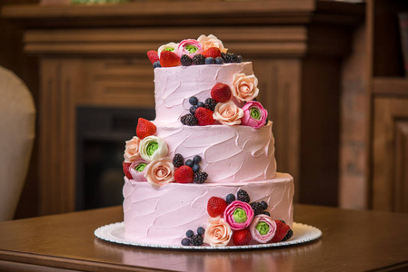 红色婚礼迎宾区三层粉红色的婚礼蛋糕, 上面点缀着浆果和花朵.