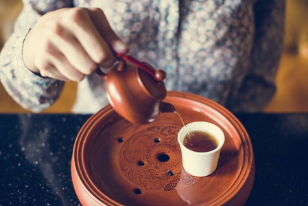 妇女倾吐茶入杯子