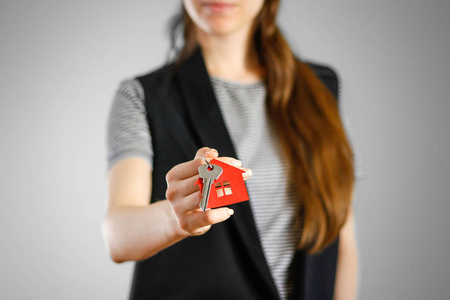 一个女孩持有房子的钥匙。钥匙环红房子