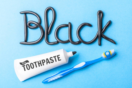 炭黑牙膏, 白牙。蓝色背景下的牙膏管子和牙科柜台上的黑字