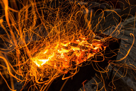 明亮的橙色火花从篝火上长期暴露和燃烧的煤。动态线跟踪
