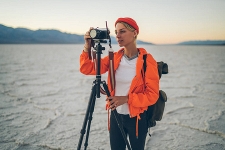 专业女摄影师用相机和三脚架制作美丽风景图片, 熟练的记者拍摄恶水盆地独特景观的视频