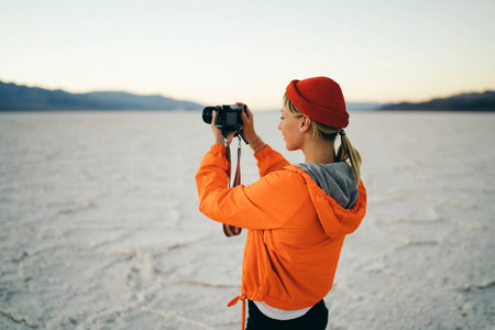 探索加州自然地标的年轻女子拍摄自然景观照片, 女摄影师在死亡谷徒步旅行期间享受风景荒凉的环境