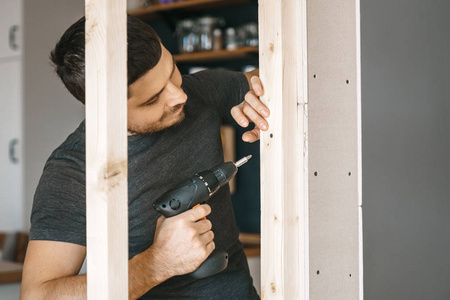 穿灰色衣服的男士们做螺丝刀, 把窗户上的木架固定在石膏板隔板上。自我修复
