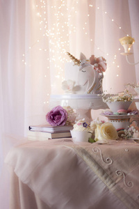 用器皿和成堆的书在桌子上装饰着独角兽的鲜花和枪口照片