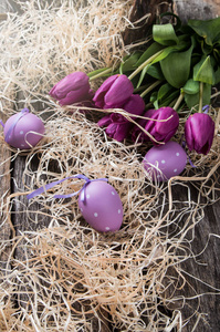 复活节彩蛋和木制的桌子上的花。在板材上春天概念