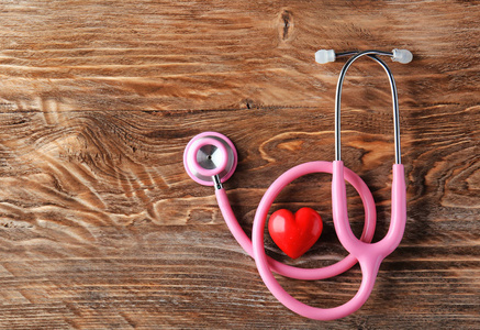 听诊器和红色的心脏在木质背景。医疗保健理念