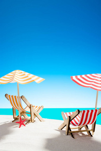 两个阳光躺椅下的沙滩上的沙滩上的海洋和天空与复制空间
