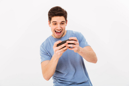 兴奋的男子在休闲 t恤玩在线游戏智能手机