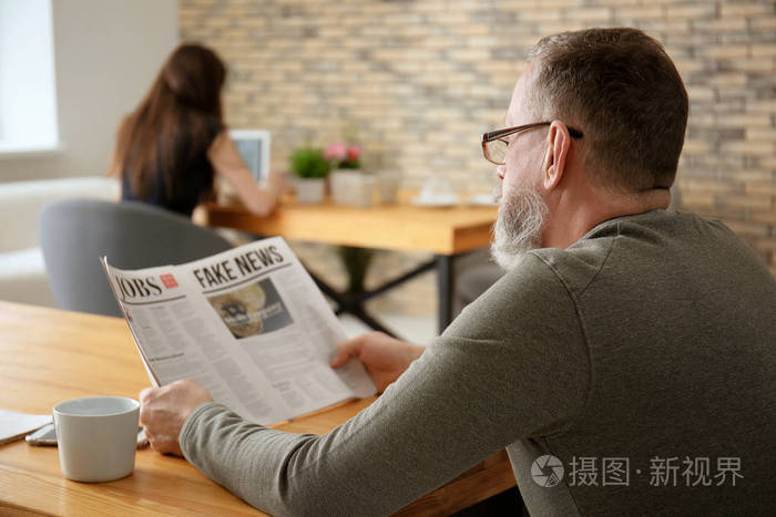 在咖啡馆读报纸的资深人