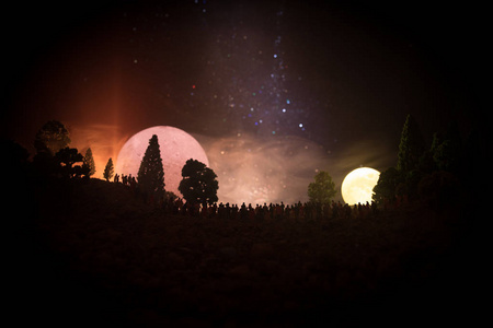 一大群人在夜里在森林里看着大满月的身影。装饰的背景与夜空的星星, 月亮和空间元素。选择性聚焦