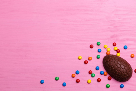 巧克力复活节彩蛋和五颜六色的糖果在一个明亮的粉红色木质背景。复活节概念