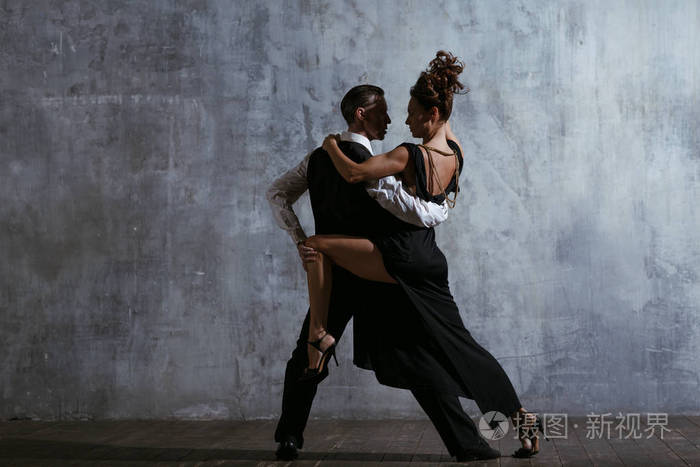 年轻俏丽的妇女在黑礼服和人舞蹈探戈