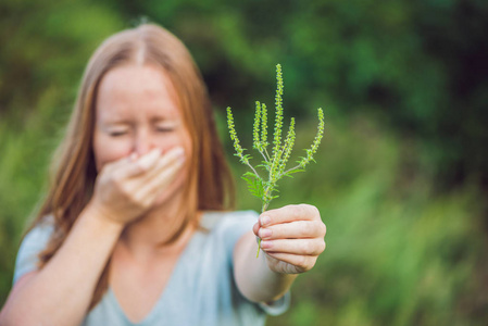由于对豚草过敏的年轻女人打喷嚏照片