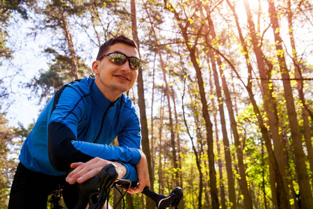 快乐的年轻人自行车在春天的森林里骑着公路自行车。休息的人
