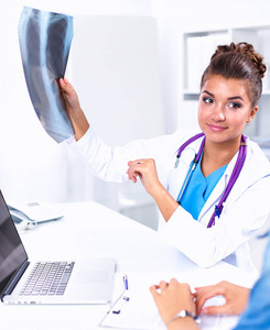 年轻的女医生学习坐在桌子上的 x 射线图像