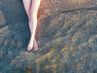 俯瞰大海的沙滩上的女性脚放松