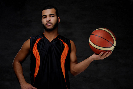 美国黑人运动员的肖像。篮球运动员在运动衫与球在黑暗的背景下