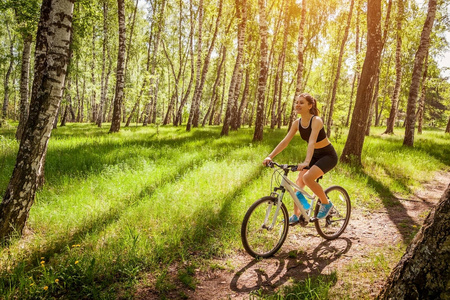 快乐的年轻女子骑车骑山地自行车在春季森林