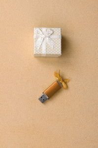 橙色 usb 存储卡与弓旁边的一个小礼品盒在橙色与一个小弓在柔软和毛茸茸的轻羊毛织物毛毯。经典时尚礼品记忆卡设计