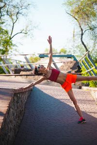 这个女孩从事晨瑜伽。一个女人在公园里训练。伸展。积极的生活方式