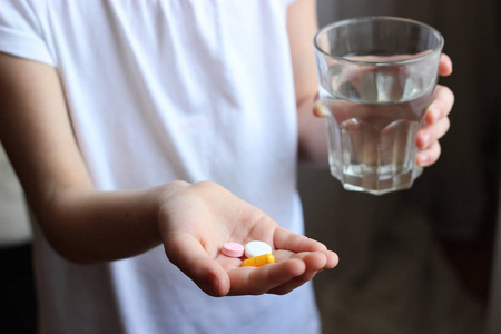 孩子手中的药片和一杯水。孩子手中的药片。儿童疾病。健康概念