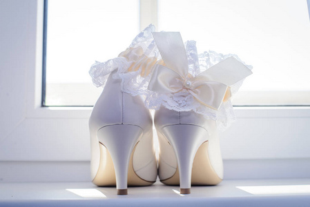 白色婚礼新娘鞋和吊袜带在窗台上, 后视图