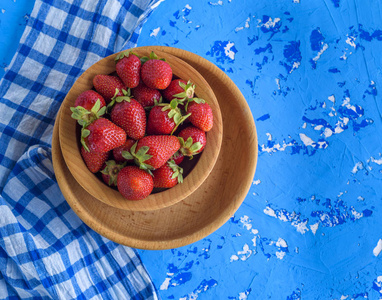 新鲜成熟的红色草莓在棕色木制圆板上蓝色餐巾, 顶部视图
