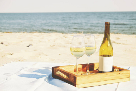 浪漫的晚餐组成与昂贵的葡萄酒瓶, 空白标签和两杯在木托盘上的白色沙滩, 海洋。海景。特写, 背景, 复制空间