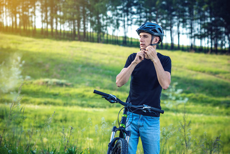 骑自行车的人在绿色自然的背景下戴着一顶运动的灰色头盔。自行车运动中的强制保护概念