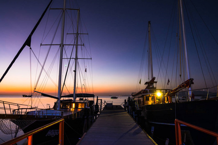 美丽的黄昏日落和紫色的天空越过海在码头, 惊人的日落看着船停泊在码头