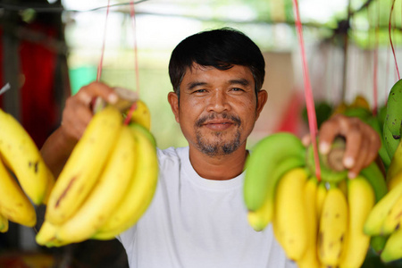 泰国当地市场出售黄色香蕉的男子