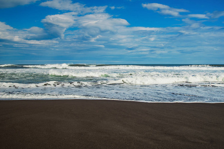 Halaktyr 海滩。堪察加。俄罗斯联邦。太平洋漆黑的黑色沙滩。石头山和黄色草在背景。浅蓝色天空