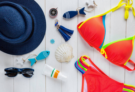 女性夏季配件 草帽, 罗盘, 贝壳, 泳装, 眼镜, 太阳喷雾, 在木背景的鱼。旅游, 夏季销售理念