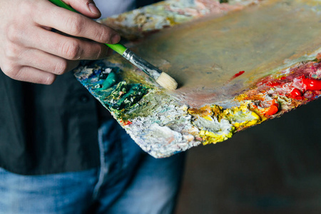 艺术家拿着颜料和刷子的调色板, 准备在画布上作画。混合油颜料