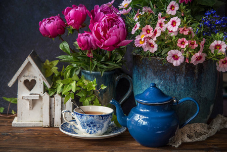 美丽的花朵在花瓶和杯茶在木桌, 夏季装饰