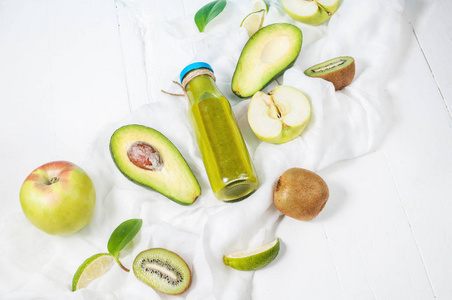 绿色冰沙在瓶配牛油果 苹果和猕猴桃白色木制背景上