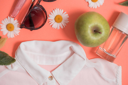在粉红色的背景下, 女性节日服装和饰物的平躺拍摄。甘菊花和苹果