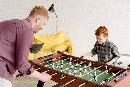 快乐的红头发的父亲和儿子一起玩桌上足球